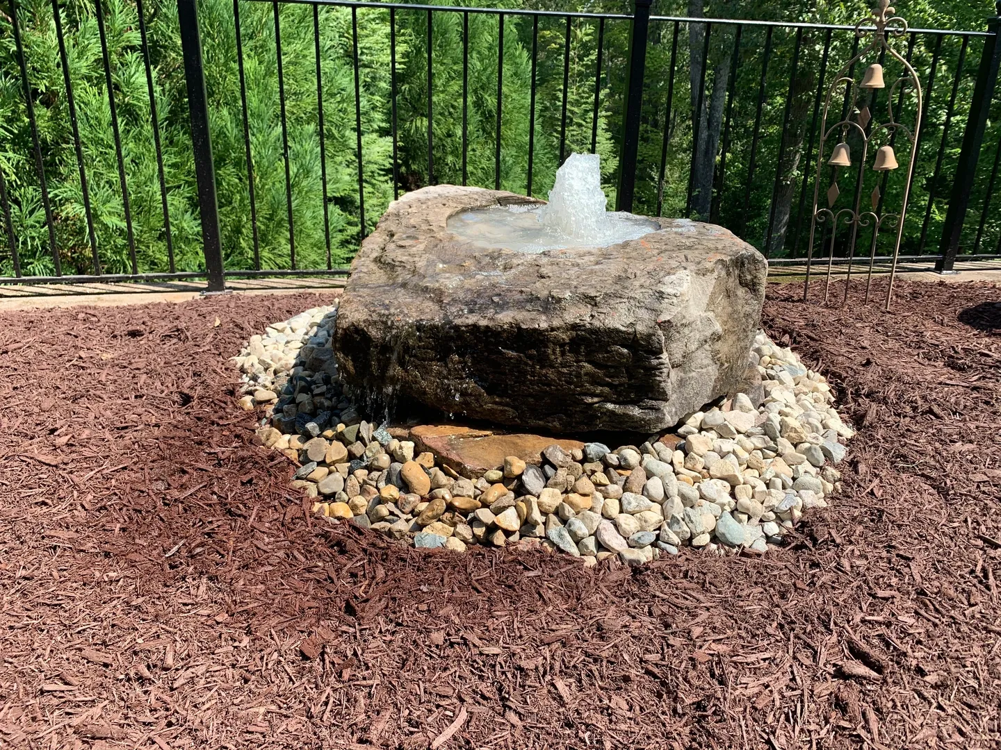 A fountain made of rocks and sand in the middle of a garden.