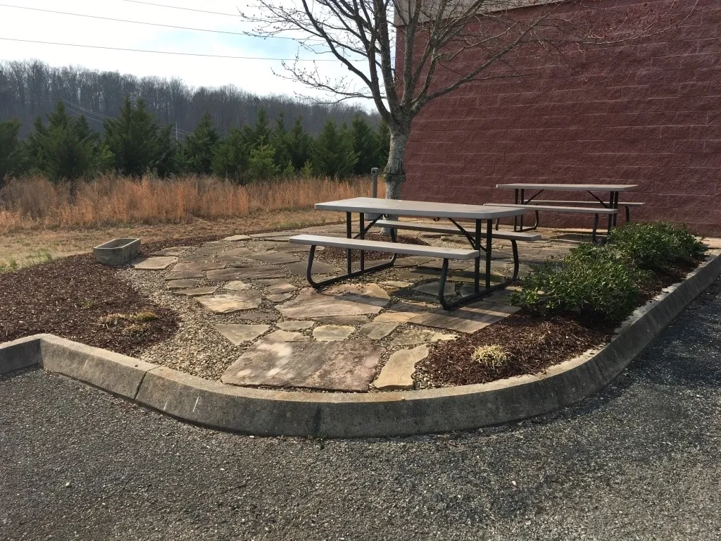 A picnic table in the middle of a circular stone patio.